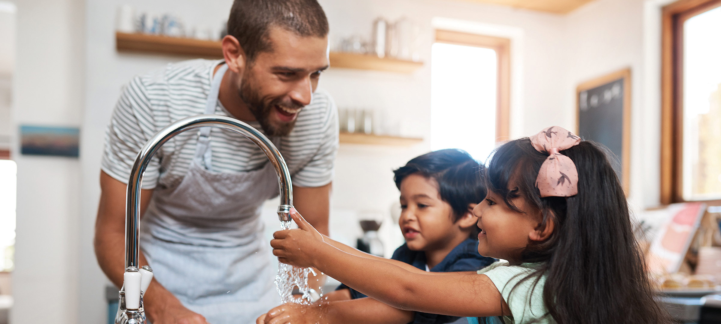 Adult and kids at a sink.